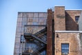 Low angle view of a wooden staircase on the outside of a red brick building, leading to different levels of an apartment or Royalty Free Stock Photo