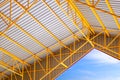 Low angle view of yellow metal roof beams and aluminum corrugated tile roof of industrial building with blue sky Royalty Free Stock Photo