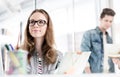 Low angle view of young attractive businesswoman sitting on her desk against colleague in office Royalty Free Stock Photo