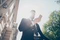 Low angle view of a young business man in a classy suit is checking his timetable by pda on the street at the sunny summer day. Ha Royalty Free Stock Photo