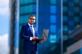 Low angle view of young confident businessman holding laptop and Royalty Free Stock Photo