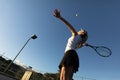 Low angle view of young female caucasian tennis player serving ball at court against clear blue sky Royalty Free Stock Photo