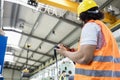 Low angle view of young manual worker operating crane in factory Royalty Free Stock Photo