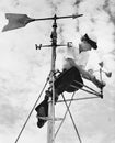 Low angle view of a young woman mending a weather vane Royalty Free Stock Photo