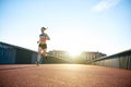 Low angle of woman running down bridge with sun Royalty Free Stock Photo