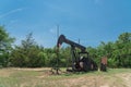 Working pump jack pumping crude oil at oil drilling site in rural USA Royalty Free Stock Photo