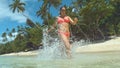 LOW ANGLE: Young girl on fun summer vacation runs in refreshing glassy ocean.