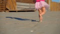 The low-angled shooting of legs of little girl in pink runnung on the beach