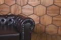 Low black leather sofa with a round armrest set on hexagon wood-panelled wall background