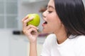 Low calories snack for wellbeing health concept. close up asian young woman bite green apple during dieting meal Royalty Free Stock Photo