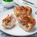 Low carb paleo meat cups, stuffed with champignons, bacon and cheese, garnished with green onion, on plate, square format