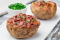 Low carb paleo meat cups, stuffed with champignons, bacon and cheese, garnished with green onion, on white plate, horizontal