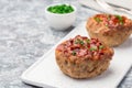 Low carb paleo meat cups, stuffed with champignons, bacon and cheese, garnished with green onion, on white plate, horizontal, copy