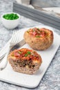 Low carb paleo meat cups, stuffed with champignons, bacon and cheese, garnished with green onion, on white plate, vertical