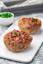 Low carb paleo meat cups, stuffed with champignons, bacon and cheese, garnished with green onion, on white plate, vertical