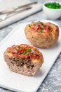 Low carb paleo meat cups, stuffed with champignons, bacon and cheese, garnished with green onion, on white plate, vertical