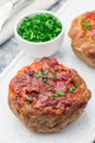 Low carb paleo meat cups, stuffed with champignons, bacon and cheese, garnished with green onion, on white plate, vertical,