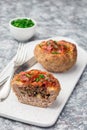 Low carb paleo meat cups, stuffed with champignons, bacon and cheese, garnished with green onion, on white plate, vertical, copy