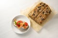 Low carb protein bread with seeds on baking paper and a sandwich with salmon, tomatoes and parsley garnish on a white table,