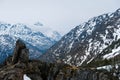 Low clouds hang over snow covered mountains with lichen covered and large stones in foreground Royalty Free Stock Photo