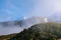 Low clouds hovering over mountain ridge and snow covered peaks. Egmont National Park, New Zealand Royalty Free Stock Photo