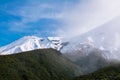 Low clouds lifting over mountain ridge and snow covered peaks. Natural background Royalty Free Stock Photo