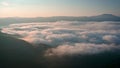 Low clouds and morning mists between the mountain slopes at sunrise