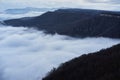 Low clouds, view of winter forest and mountains from observation deck, horizontal picture of amazing natural phenomenon. Beautiful Royalty Free Stock Photo