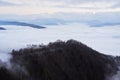 Low clouds, view of winter forest and mountains from observation deck, horizontal picture of amazing natural phenomenon. Beautiful