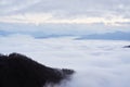 Low clouds, view of winter forest and mountains from observation deck, horizontal picture of amazing natural phenomenon. Beautiful Royalty Free Stock Photo