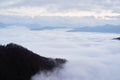 Low clouds, view of winter forest and mountains from observation deck, horizontal picture of amazing natural phenomenon. Beautiful Royalty Free Stock Photo