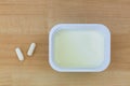 Low fat Yogurt next to white Yoghurt capsules containing culture