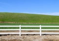 Low grassland hillside hills pasture with bright sunny blue sky and wooden white picket farm livestock fence Royalty Free Stock Photo