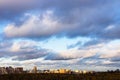 Low gray clouds in blue sky over city lit by sun Royalty Free Stock Photo