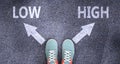 Low and high as different choices in life - pictured as words Low, high on a road to symbolize making decision and picking either Royalty Free Stock Photo