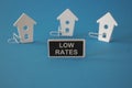 Low house rates symbol. Concept red words Low rates on wooden board near miniature houses. Beautiful blue background, copy space.