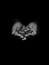 Low key black and white photo of a man holding several coins in his hands