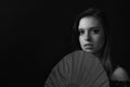 Low key black and white portrait of beautiful young woman behind the fan Royalty Free Stock Photo