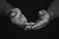 Low key, close up of hands of a faithful mature man praying, hands folded, interlaced fingers in worship to god Royalty Free Stock Photo