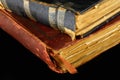 Low key closeup of very old books in poor condition on black background.