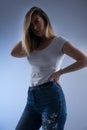 Mysterious and Alluring: Low Key Vertical Portrait of a Blonde Woman in White T-Shirt and Blue Jeans