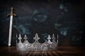 low key image of beautiful queen or king crown next to sword. fantasy medieval period. Selective focus Royalty Free Stock Photo