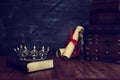 Low key image of beautiful queen/king crown, old books and feather quill ink pen over wooden table. fantasy medieval period Royalty Free Stock Photo
