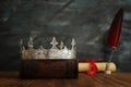 Low key image of beautiful queen/king crown, old books and feather quill ink pen over wooden table. fantasy medieval period Royalty Free Stock Photo