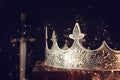 low key image of beautiful queen/king crown over antique box next to sword. fantasy medieval period. Selective focus. Glitter Royalty Free Stock Photo