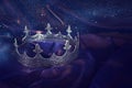 Low key image of beautiful queen/king crown over dark royal purple delicate silk. fantasy medieval period