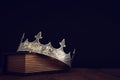 low key image of beautiful queen/king crown over old book and wooden table. vintage filtered. fantasy medieval period Royalty Free Stock Photo