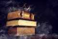 low key image of beautiful queen/king crown over old book and wooden table. vintage filtered. fantasy medieval period. mist and Royalty Free Stock Photo
