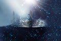 low key image of beautiful queen/king crown over wooden table. vintage filtered. fantasy medieval period. Glitter sparkle lights