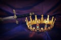 Low key image of beautiful queen/king crown and sword over dark royal purple delicate silk. fantasy medieval period